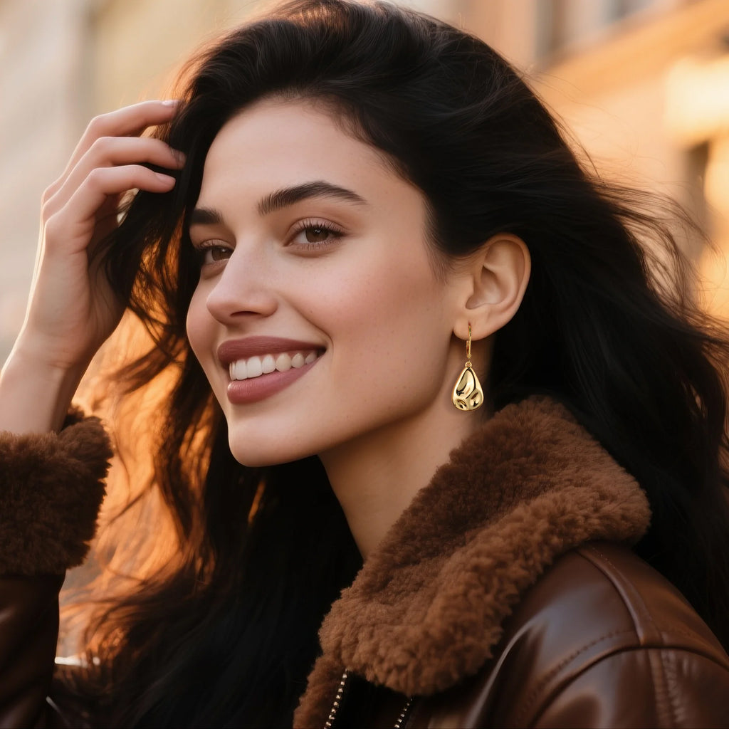 Gold waterdrop drop earrings on model, hammered texture, hook backs.