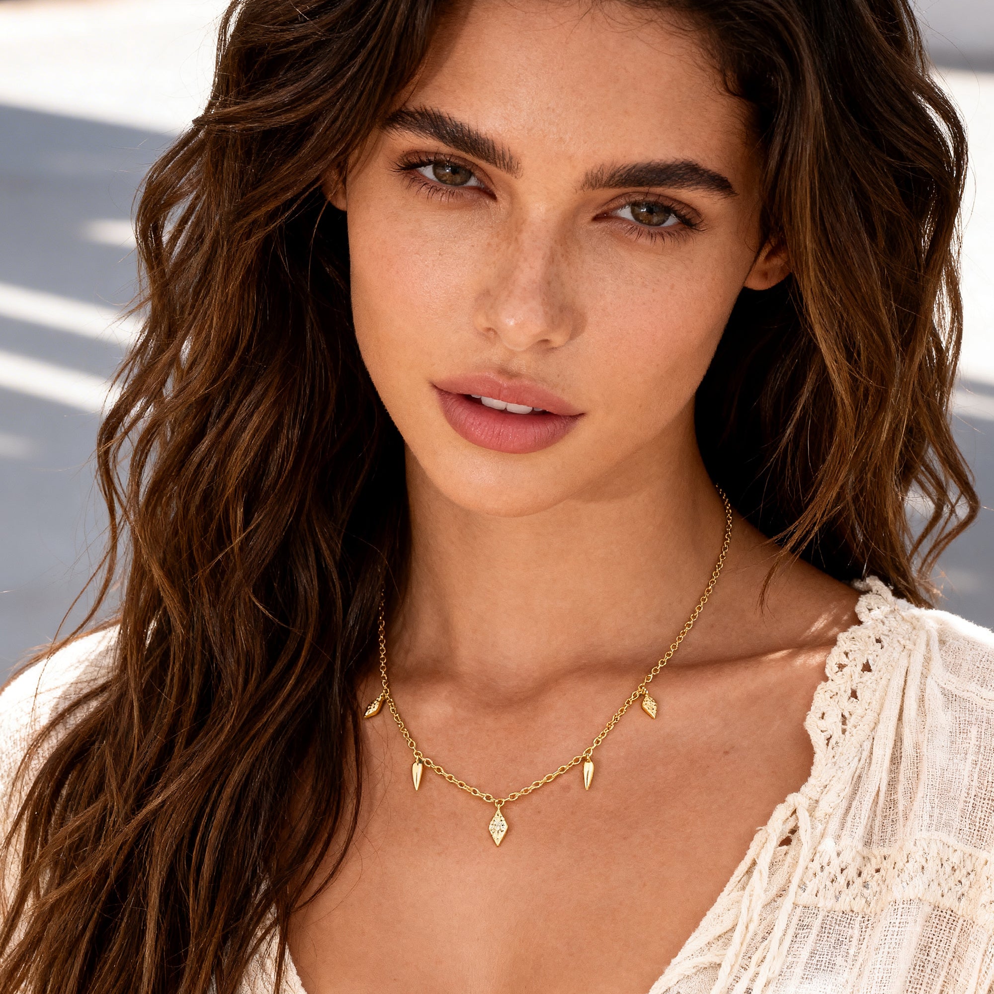 Gold geometric drop necklace on model with teardrop charms and pointed spike pendants