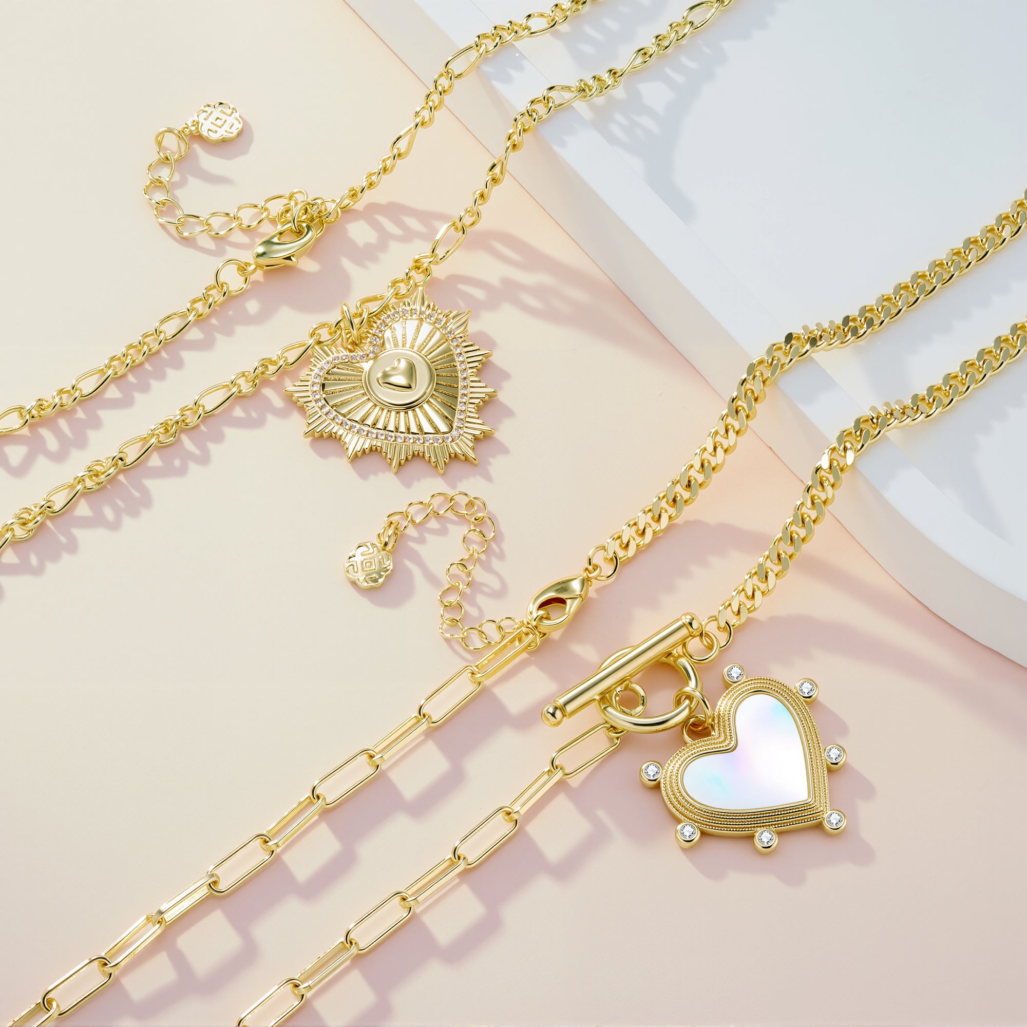Gold pearl heart charm necklace shown with layered charms and chain links