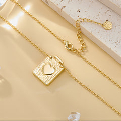 Gold heart locket pendant with textured square face and heart inset, includes small chain charm.