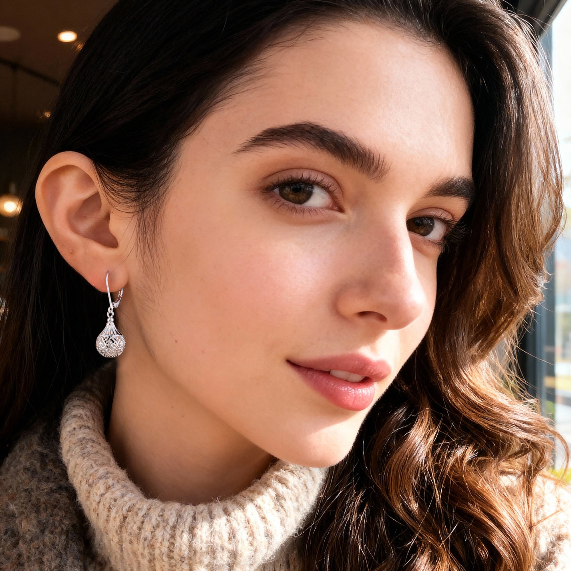Silver hollow lantern drop earrings on model, ornate filigree globe with bead detail