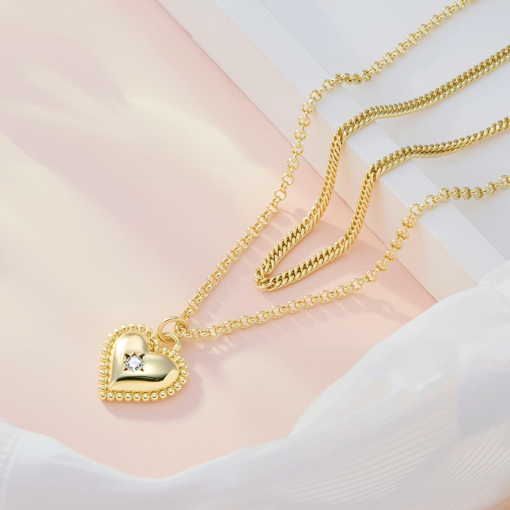 Gold heart pendant on beaded-edge bail with rope-cable chain layered with link chain