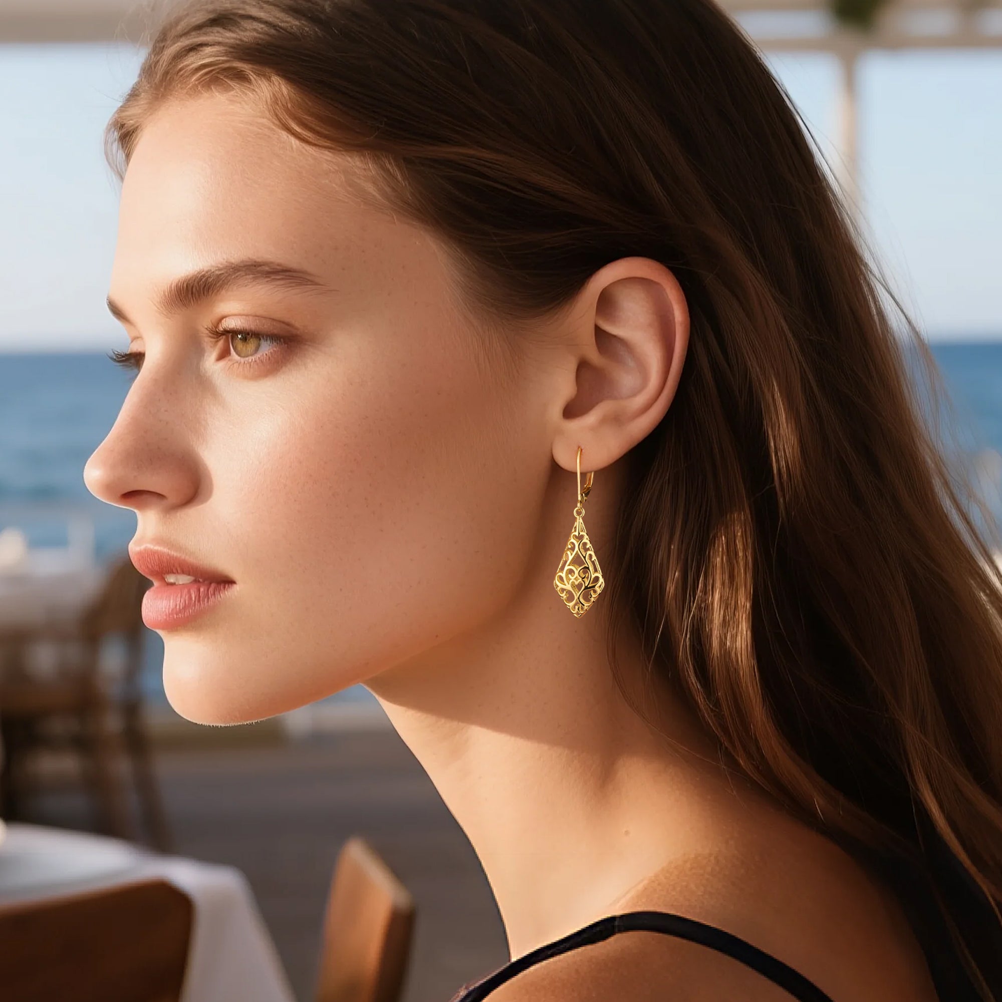 Gold-tone geometric filigree drop earrings on a model, teardrop design