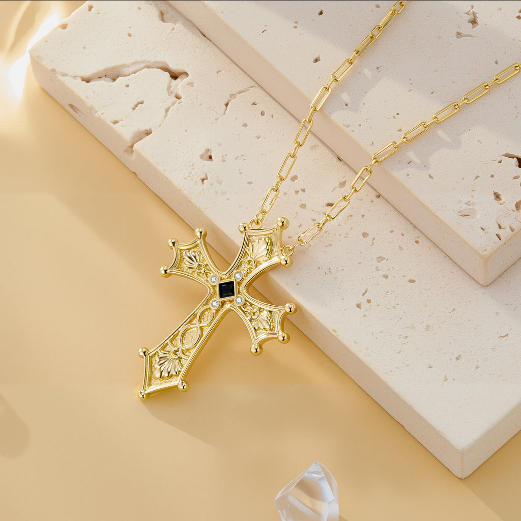 Ornate gold baroque cross pendant necklace on curb chain with dark center gem