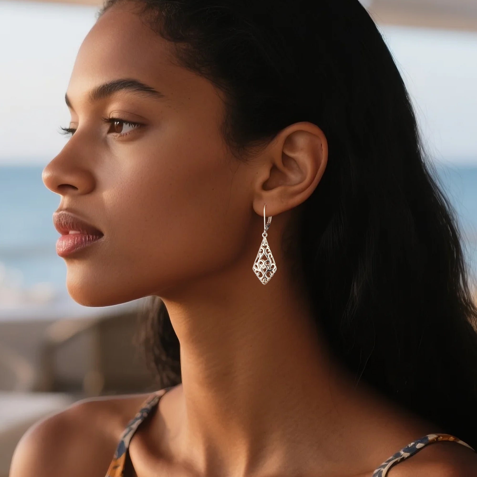 Silver-tone geometric filigree drop earrings on a model, teardrop design