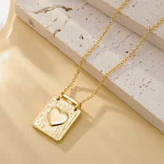 Gold textured square heart locket pendant on chain, heart emblem set in the front.
