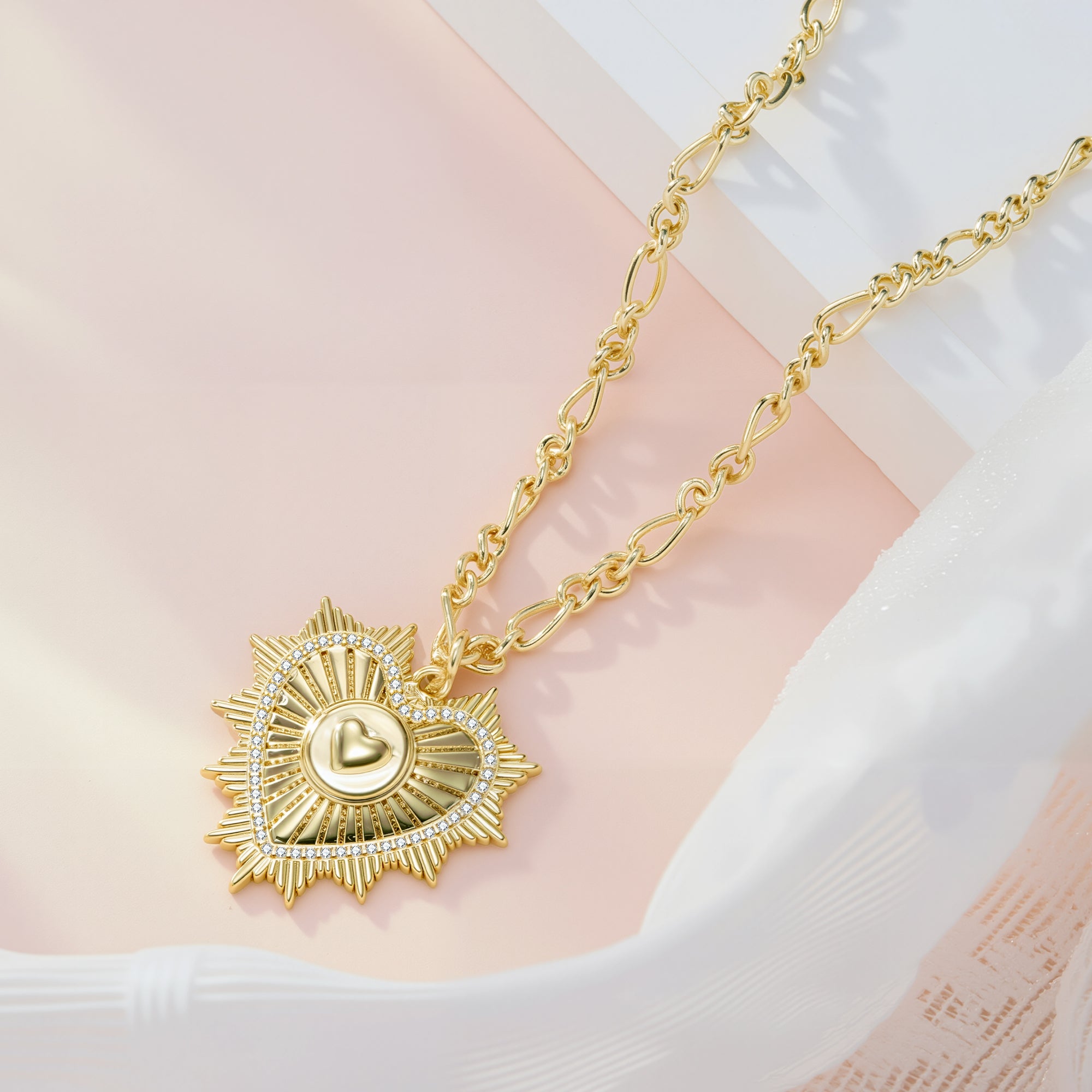 Gold Figaro chain with radiant heart pendant, close-up view
