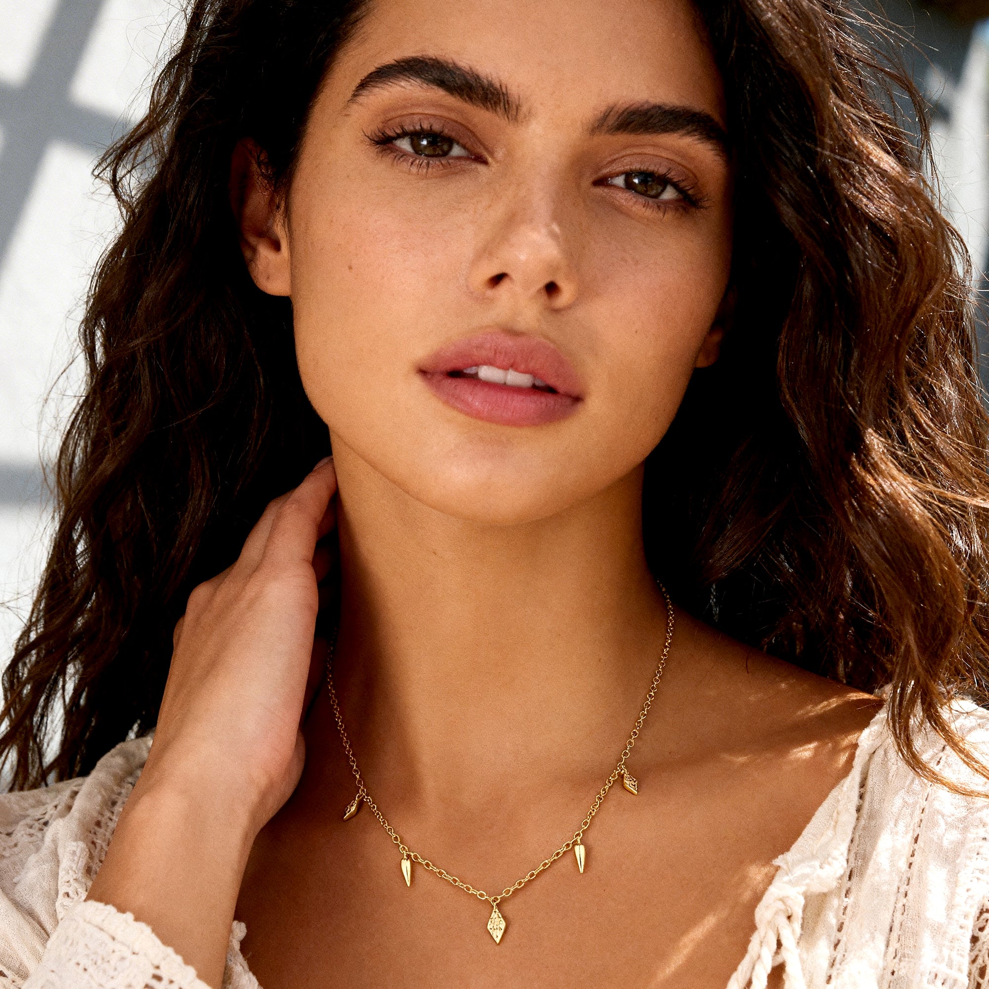 Gold geometric drop necklace on model, with small spike and teardrop charms