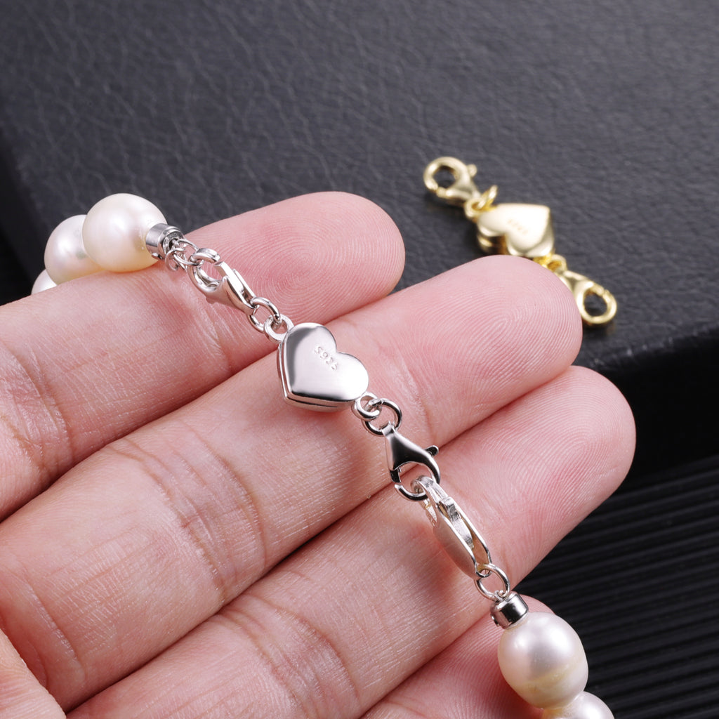 Heart magnetic bracelet clasp set with gold and silver hearts on a hand holding pearls