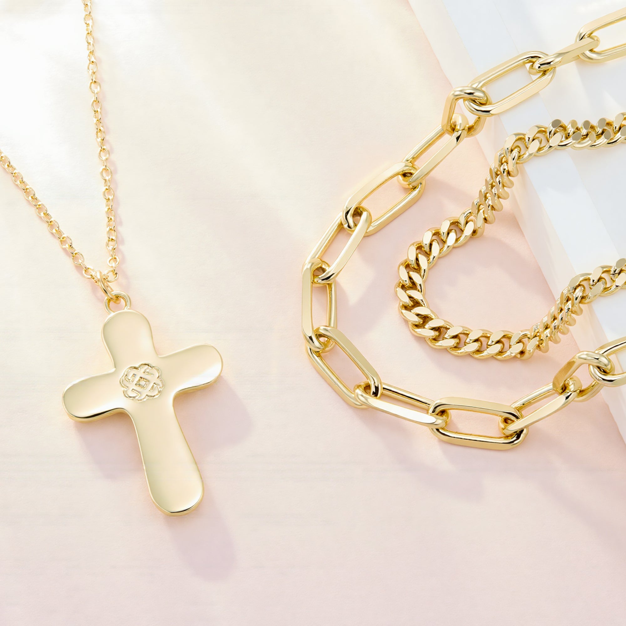 Close-up: Gold Trinity cross pendant on layered chain necklace