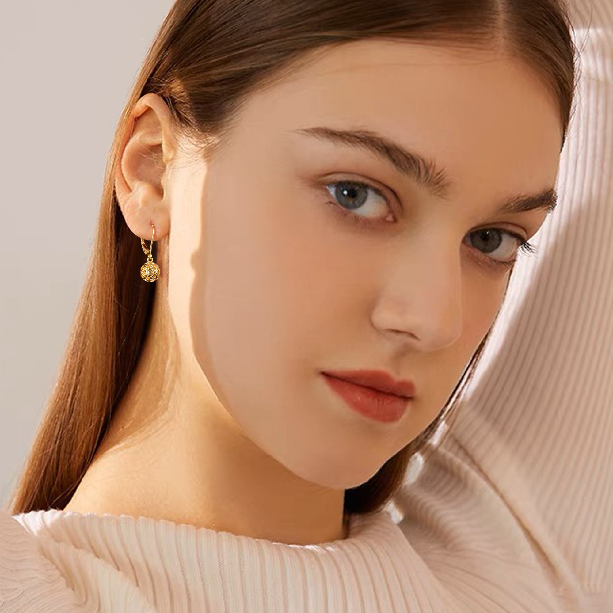 Gold skeleton ball drop earrings on ear, round heart-pattern dangle charm