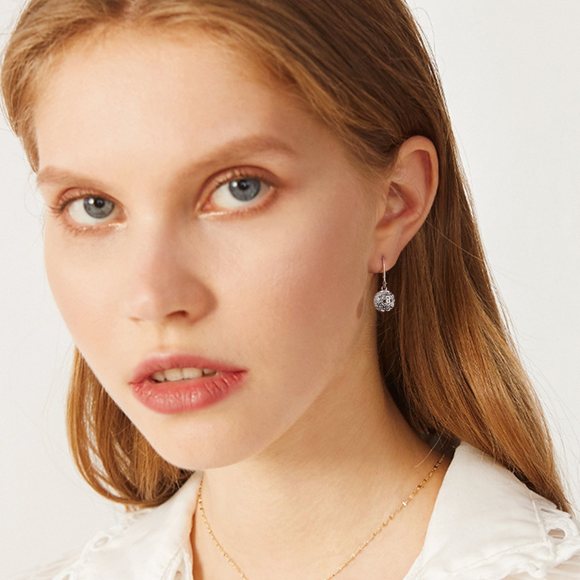 Silver skeleton ball drop earrings on ear, round heart-pattern dangle charm