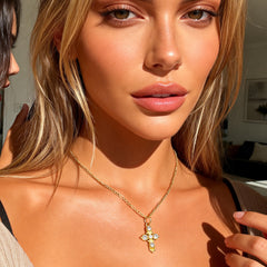 Gold cross pendant necklace with dangling charm and four small stones