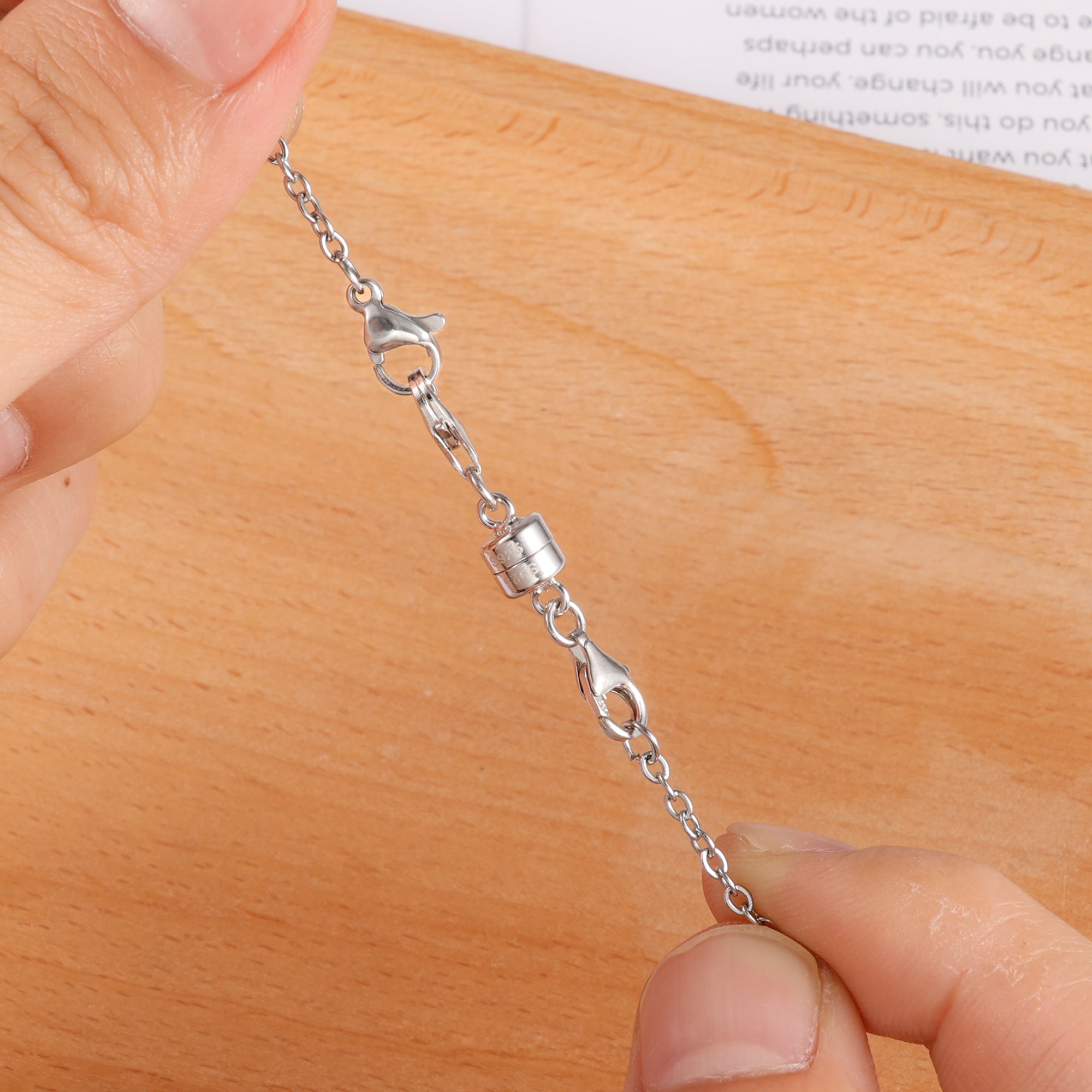 Silver magnetic necklace clasp converter close-up on chain links, held by fingers