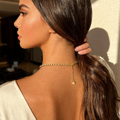 Gold-toned necklace with heart pendant and short dangling charm, side view
