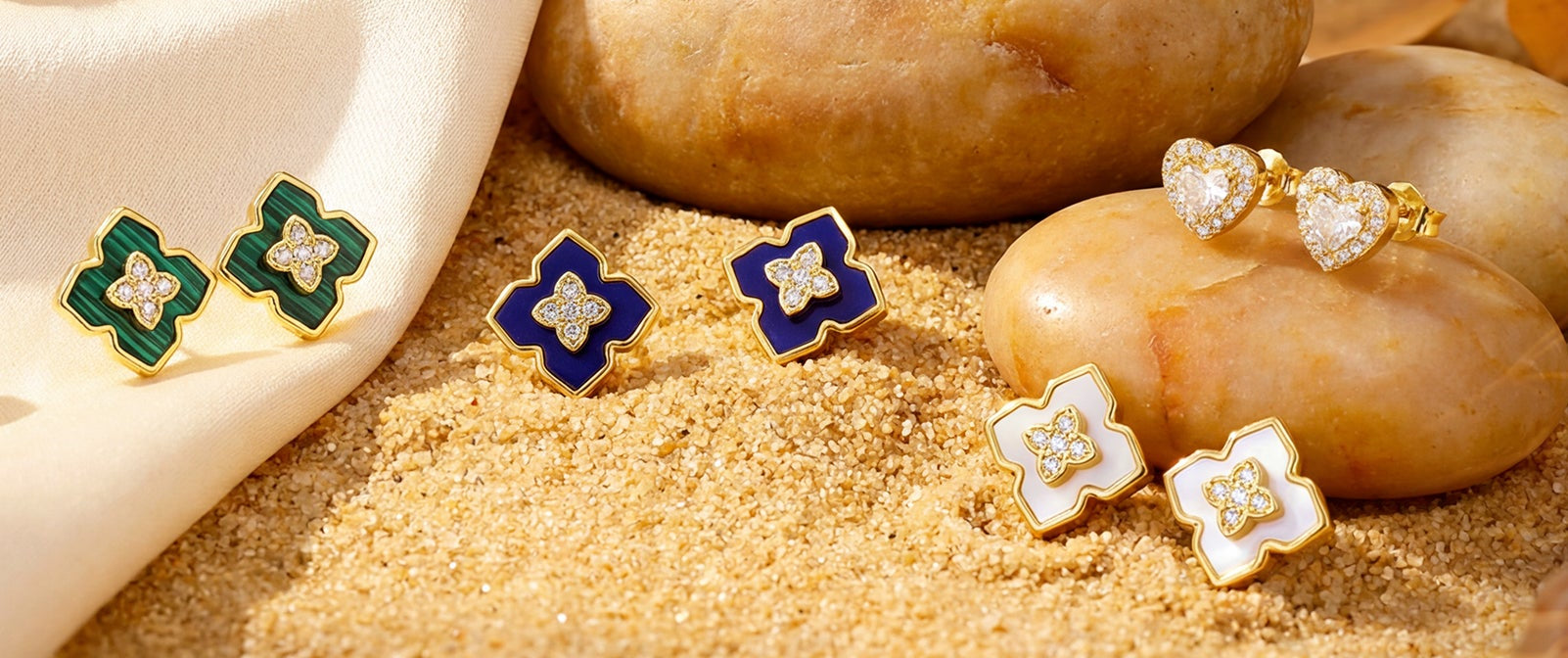 Pair of earrings on stones with dried flowers and Alefcraft logo on a brown background